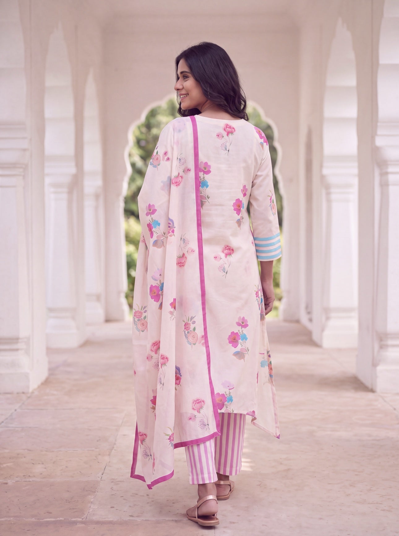 Back view of ivory floral kurta with pink bordered dupatta and striped pants
