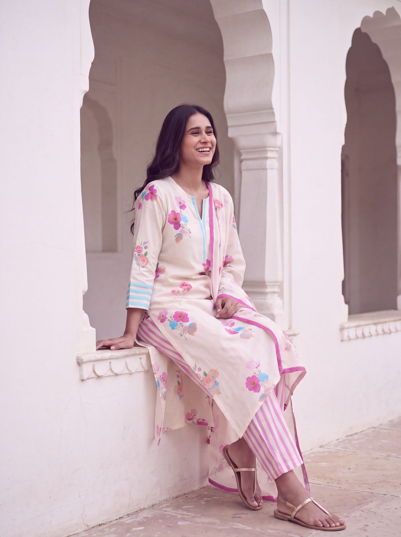 Woman sitting in ivory watercolour floral three-piece kurta set